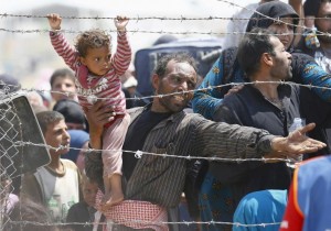 A Syrian refugee reacts as he waits behind border fences to cross into Turkey at Akcakale border gate in Sanliurfa province, Turkey