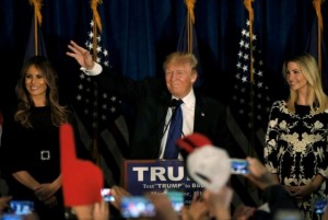 Republican U.S. presidential candidate Donald Trump reacts on stage as his wife Melania and daughter Ivanka look on at his 2016 New Hampshire presidential primary night rally in Manchester